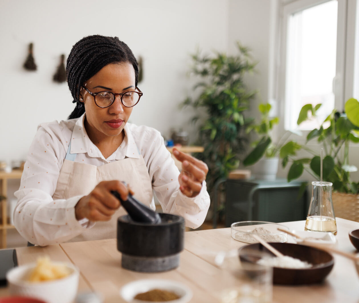 Female student setting at a table using a pestle and mortar.