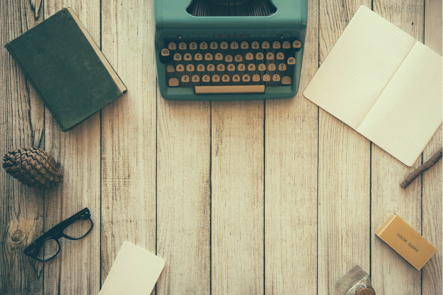 Laptop, typewriter, pen, notebook on a table