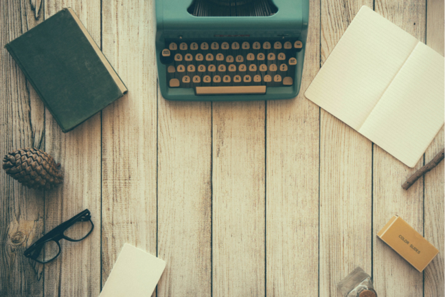 Various objects including laptop, typewriter, pen, notebook on the table