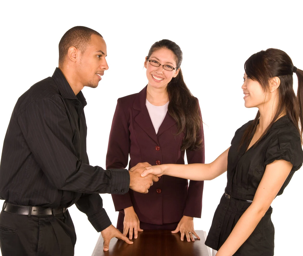 Diverse group of young professionals shaking each others' hands in agreement.