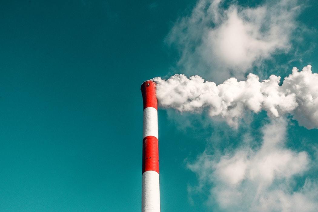 Red and white factory chimney spewing out smoke