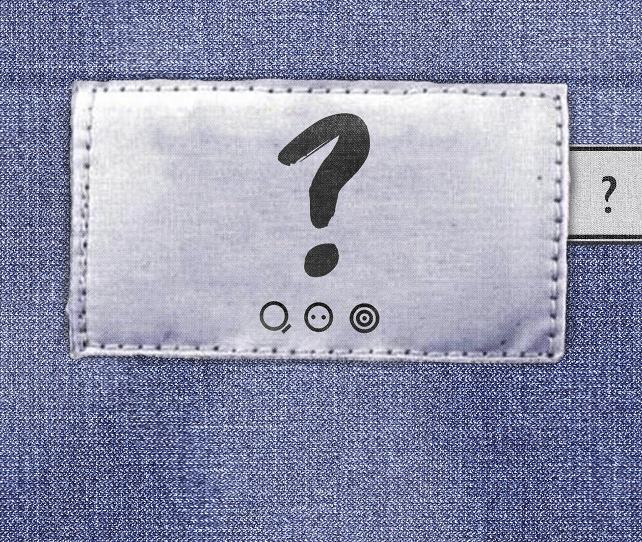 Clothing label bearing a question mark, three wash symbols with the text 'be curious', 'find out', and 'do something'. A Fashion Revolution tab appears to the right of the main label.