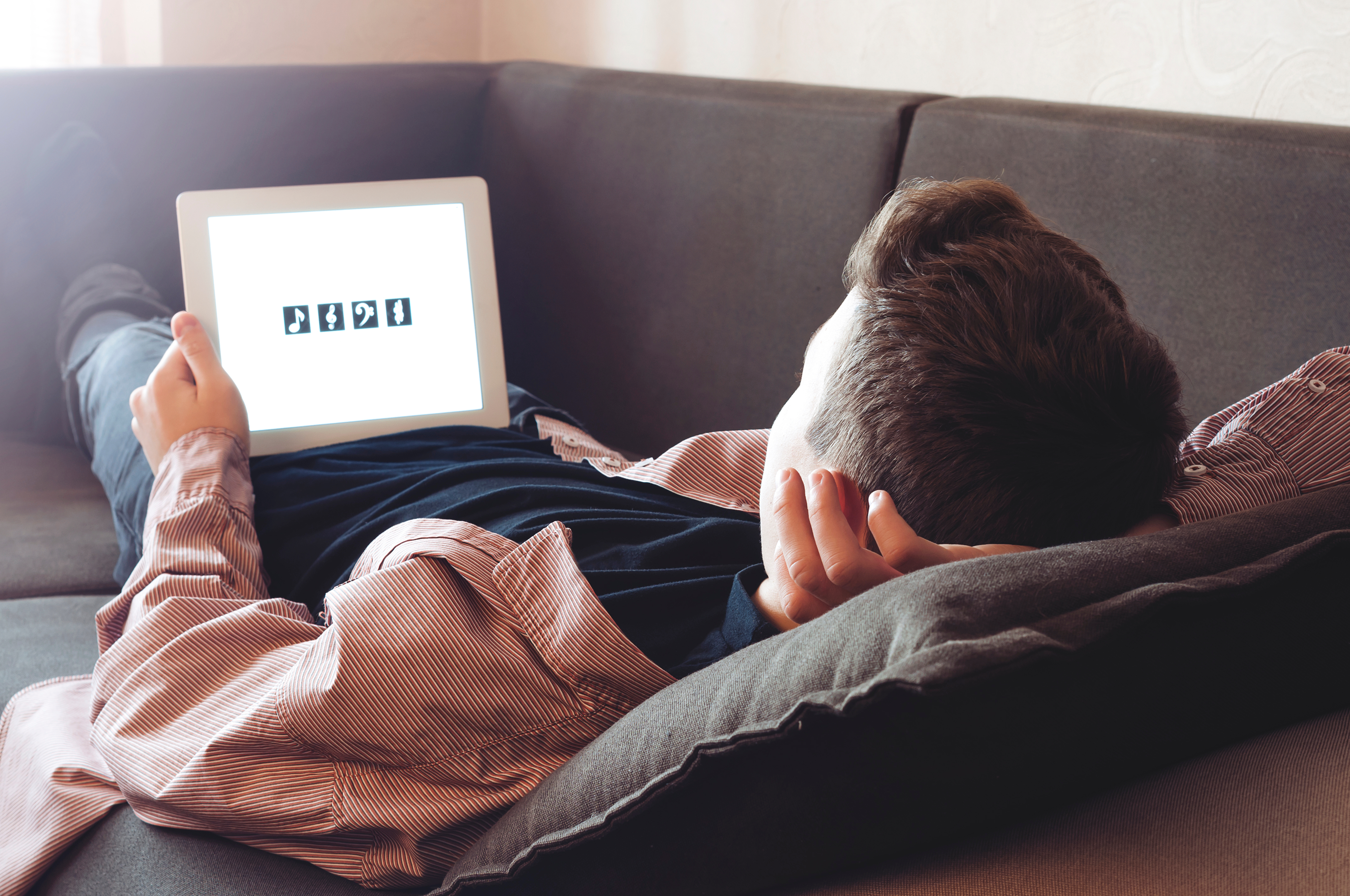 Teenager lying on a sofa looking at a tablet