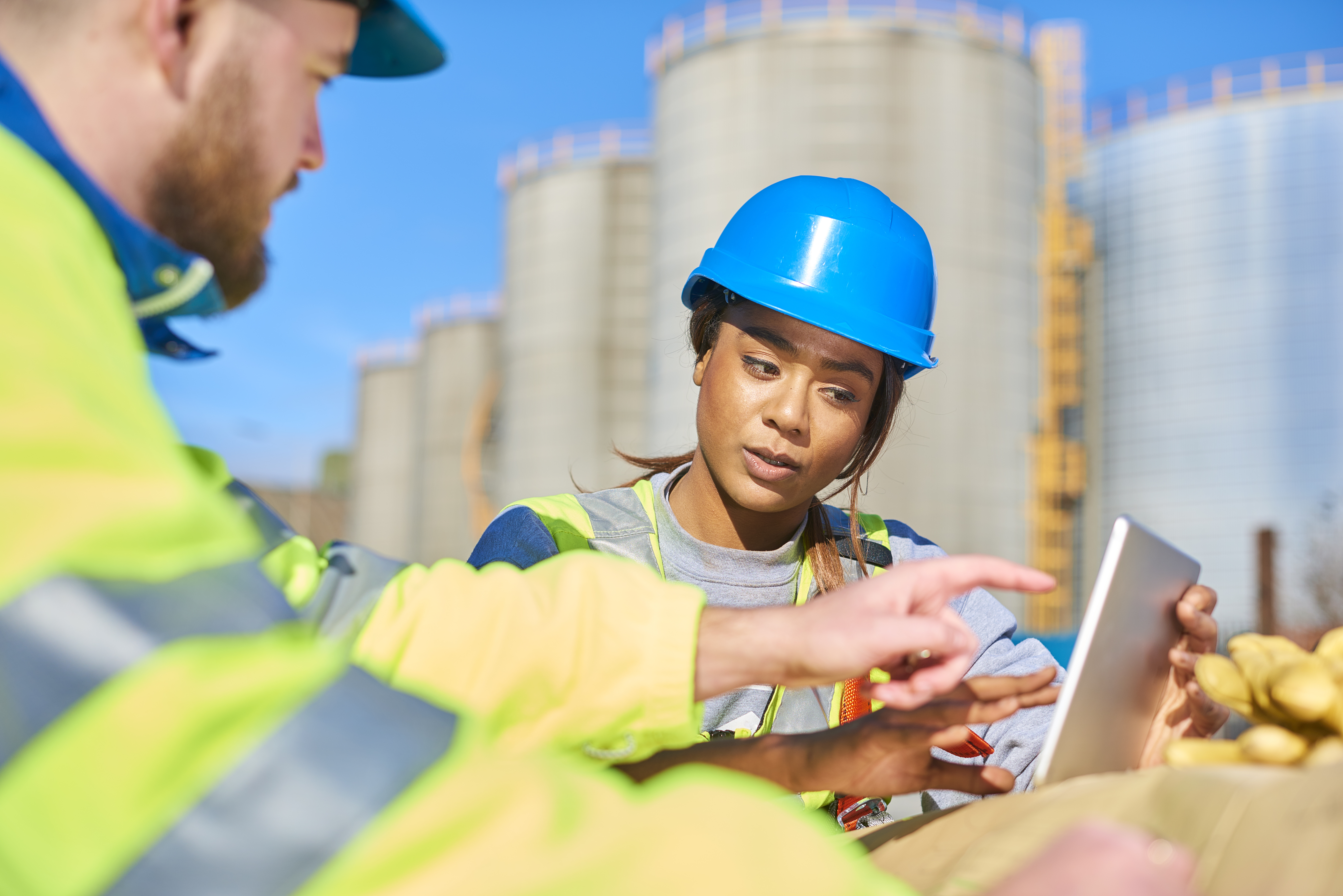 Close-up of a female construction worker looking at handheld device with male colleague