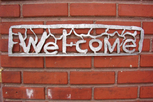 Metal "Welcome" sign on red brick wall