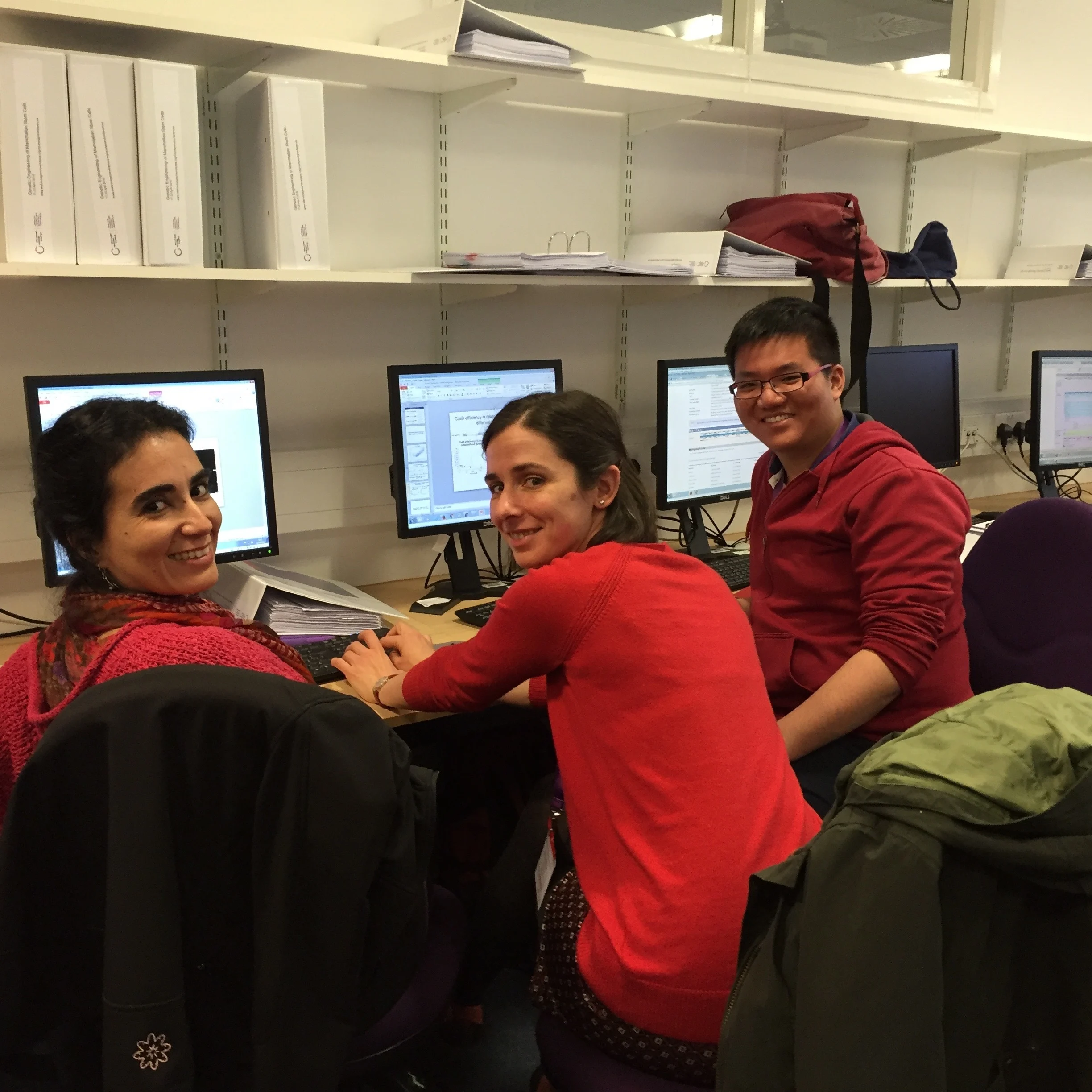 Three learners, two women and one man, working together at computers