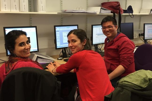 Three learners, two women and one man, working together at computers