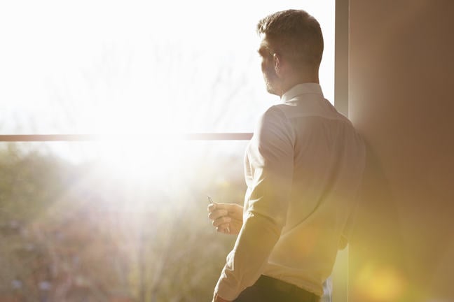 Man standing by window with sunlight