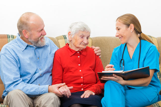 A person with an intellectual disability, with their carer and a nurse sitting on a sofa.