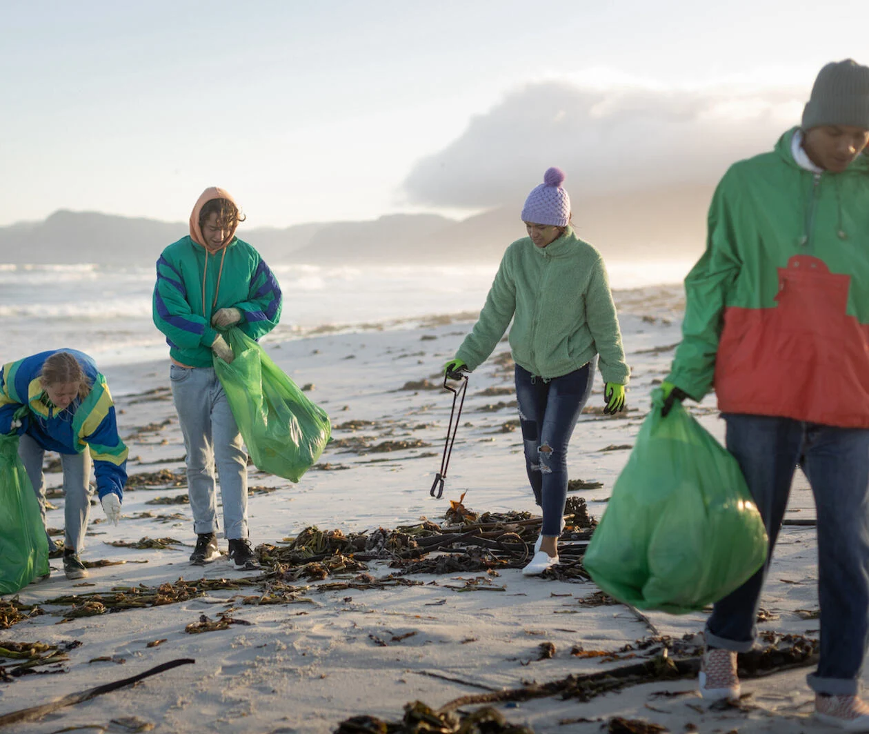 A group of socially responsible climate activists litter picking on a beach.