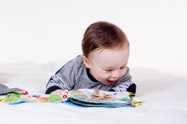 Baby laying on his stomach on a soft picture book