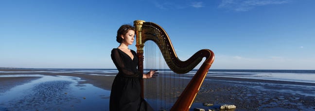 lady holding harp on Irish beach in the early evening