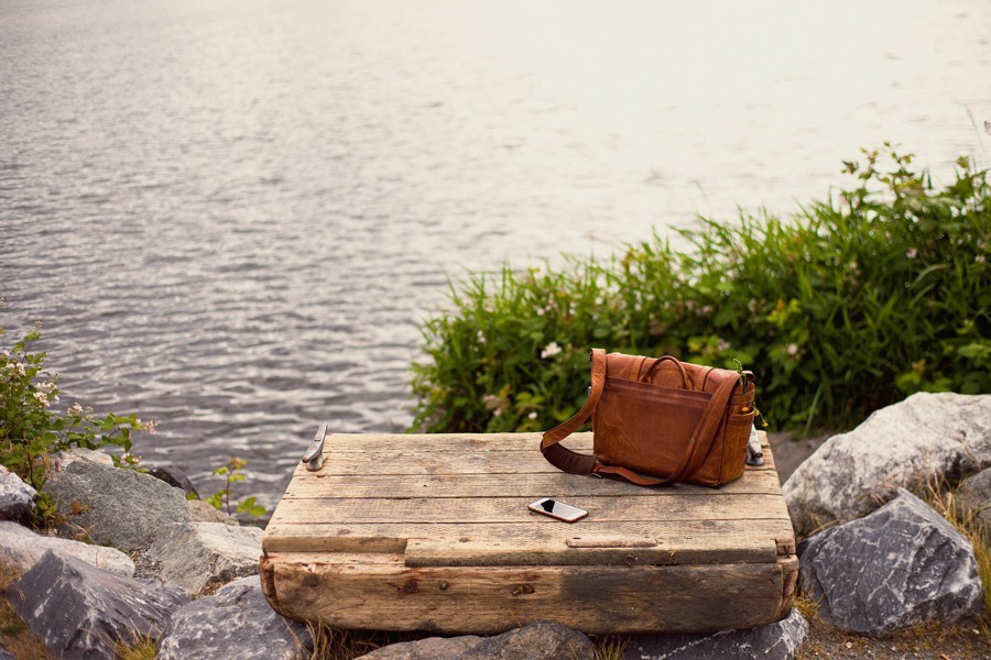 A bag and a phone on a board at a water's edge