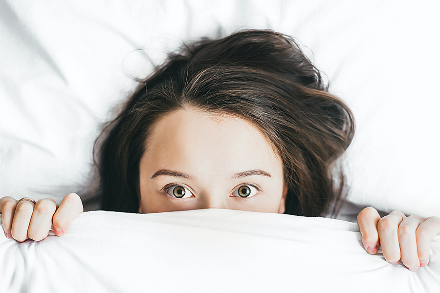 A young girl hiding under bedsheets