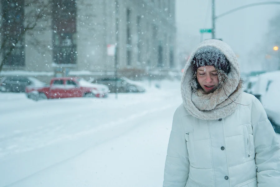 Teenage girl walks through snowfall in the street in Manhattan