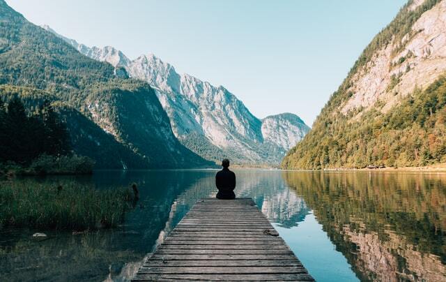 A person sitting at the end of a pier looking at a vista.