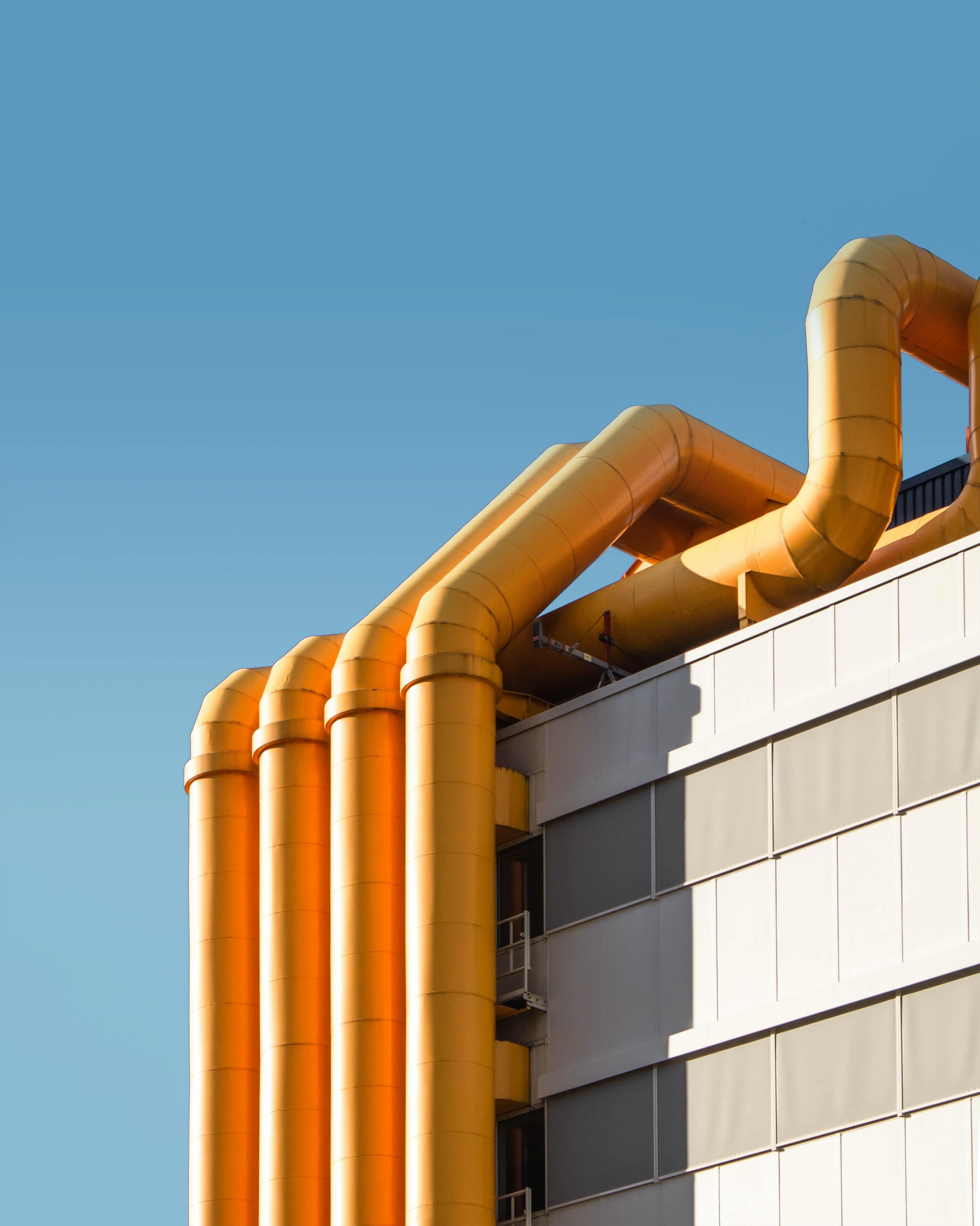 Yellow industrial pipes on the outside of a building roof and sides