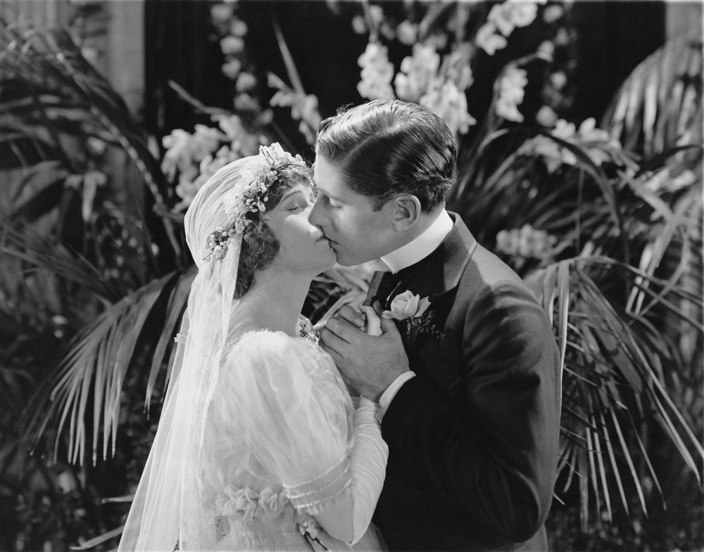 This black and white image shows a couple kissing on their wedding day