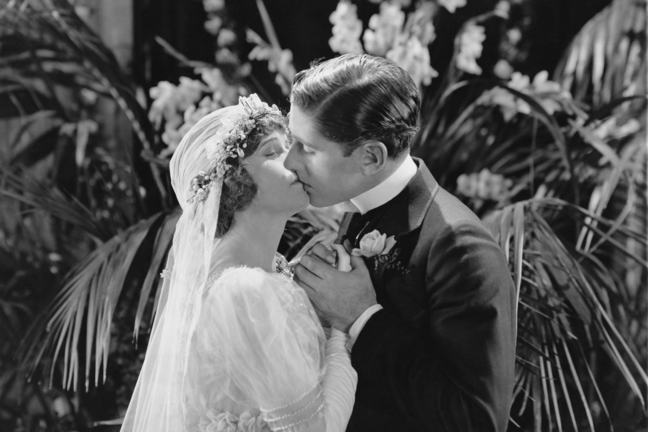 This black and white image shows a couple kissing on their wedding day