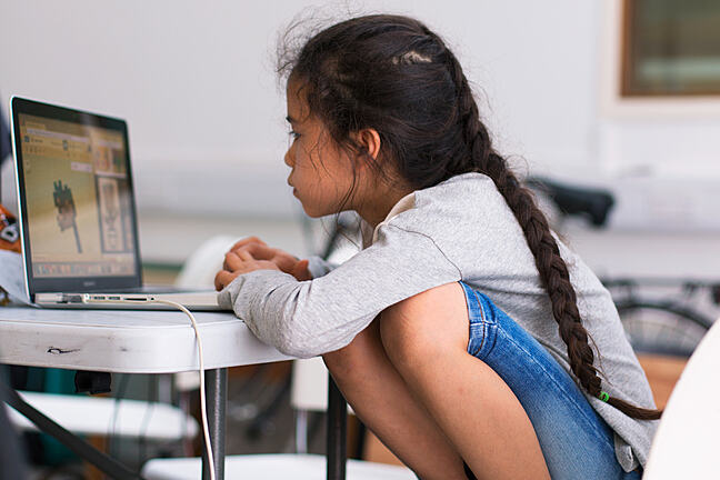 A photograph of a young girl programming on her own