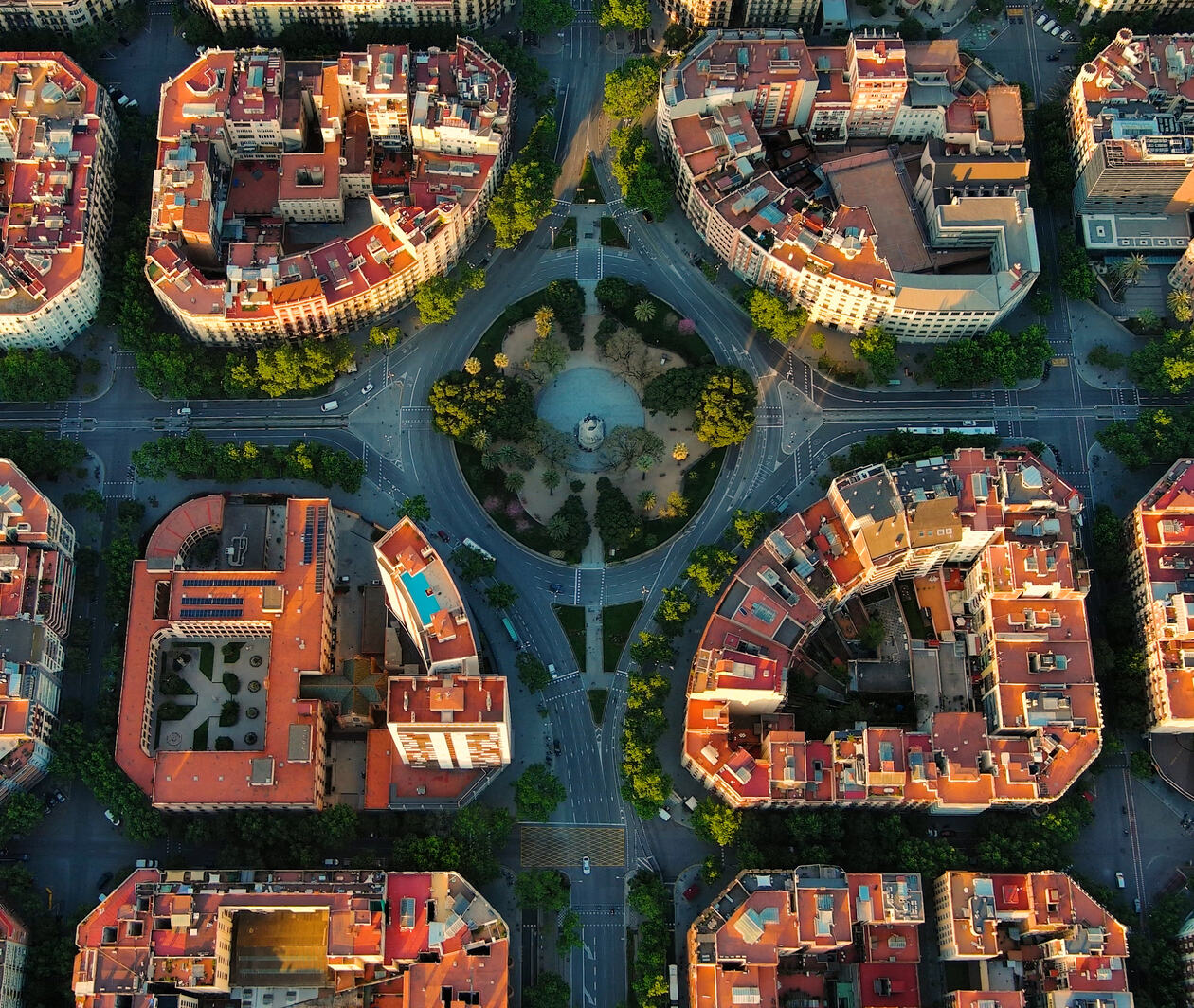 An aerial view of Barcelona residential blocks with roads intersecting and trees lining streets