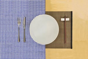 Intercultural communication, symbolised by a plate with a knife and fork on one side, and chop sticks on the other