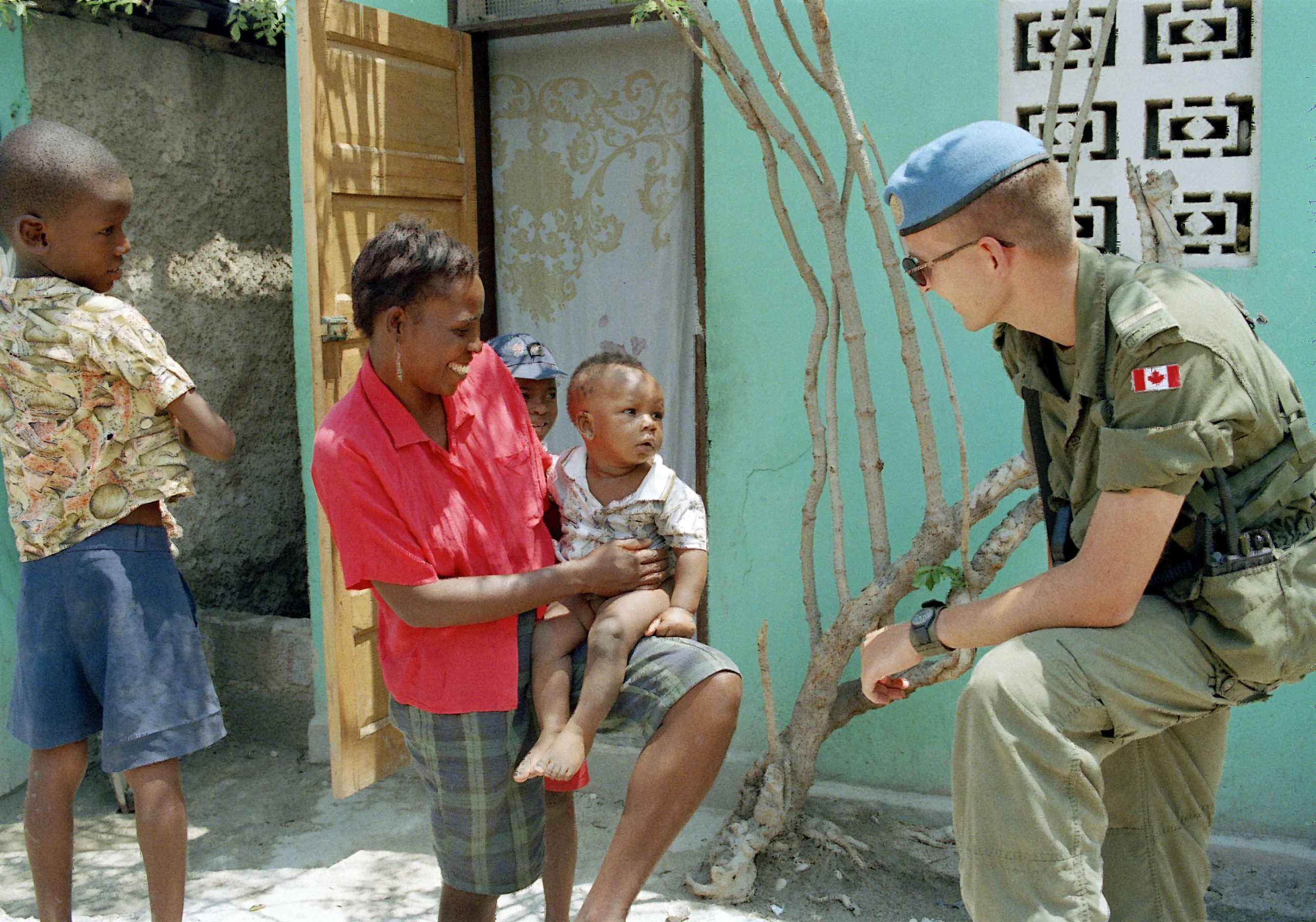 A group of UNSMIH peacekeeping soldiers from the Canadian Battalion stop to talk with a Haitian woman in Port-au-Prince.