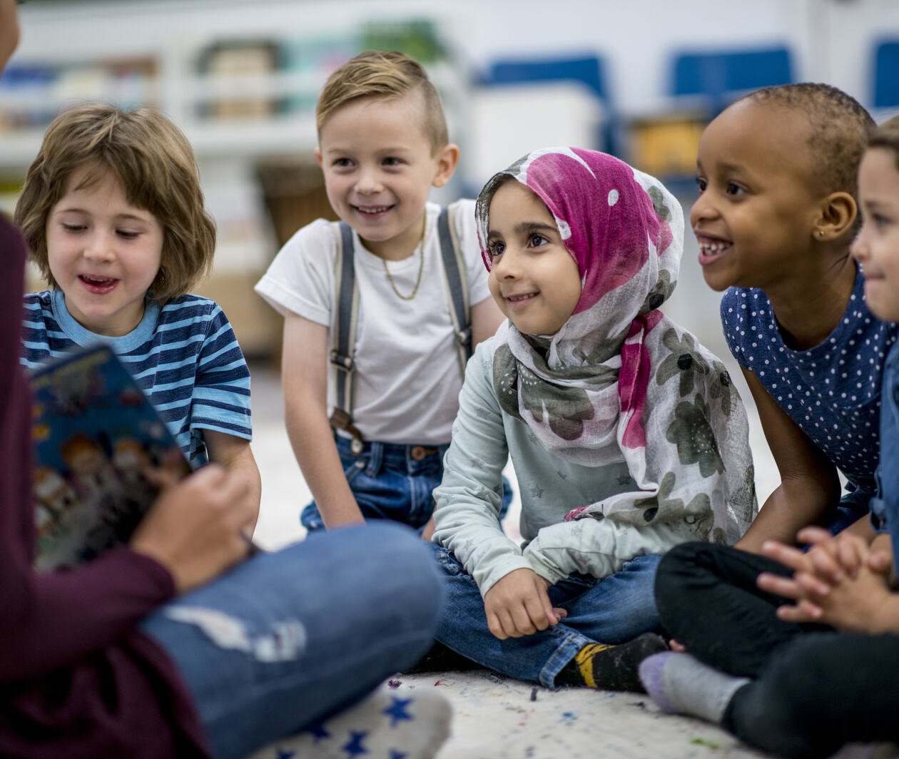 Children sitting listening to a teacher reading