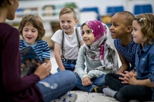 Children sitting listening to a teacher reading