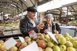 A man and woman buying fruit from a market stall