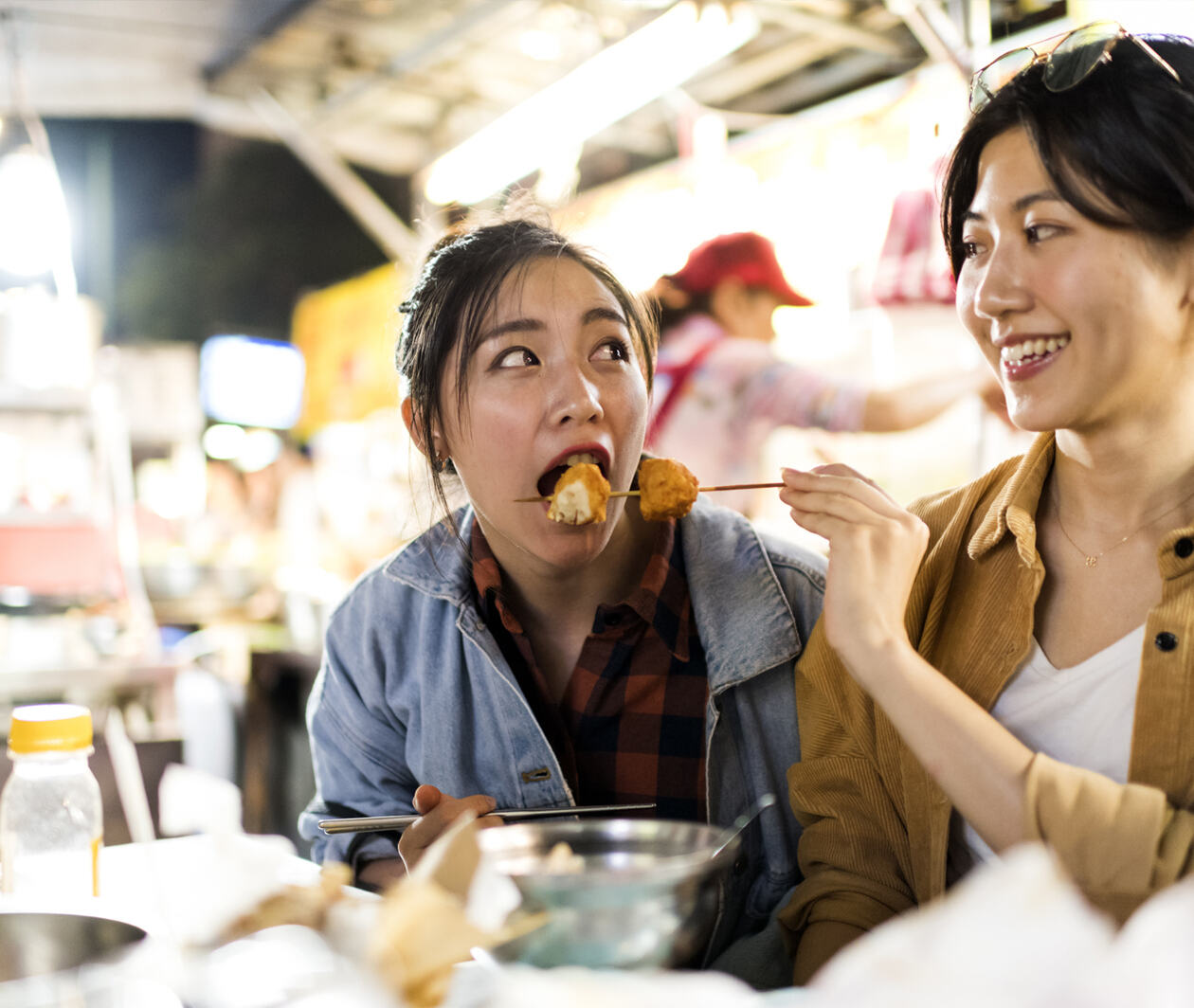 2 friends trying different street foods at night market in Taiwan.