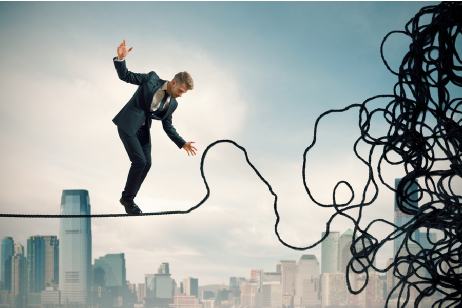 Man trying to walk on a tangled tightrope. Cityscape in the background