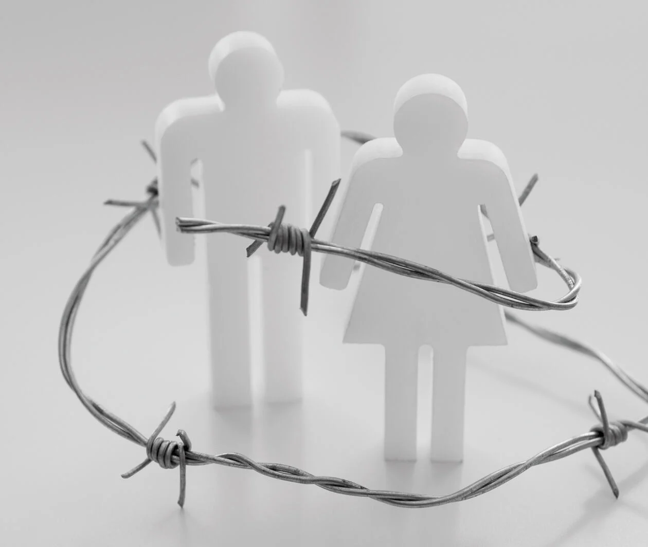 doll of a man and a women surrounded by barbed wire