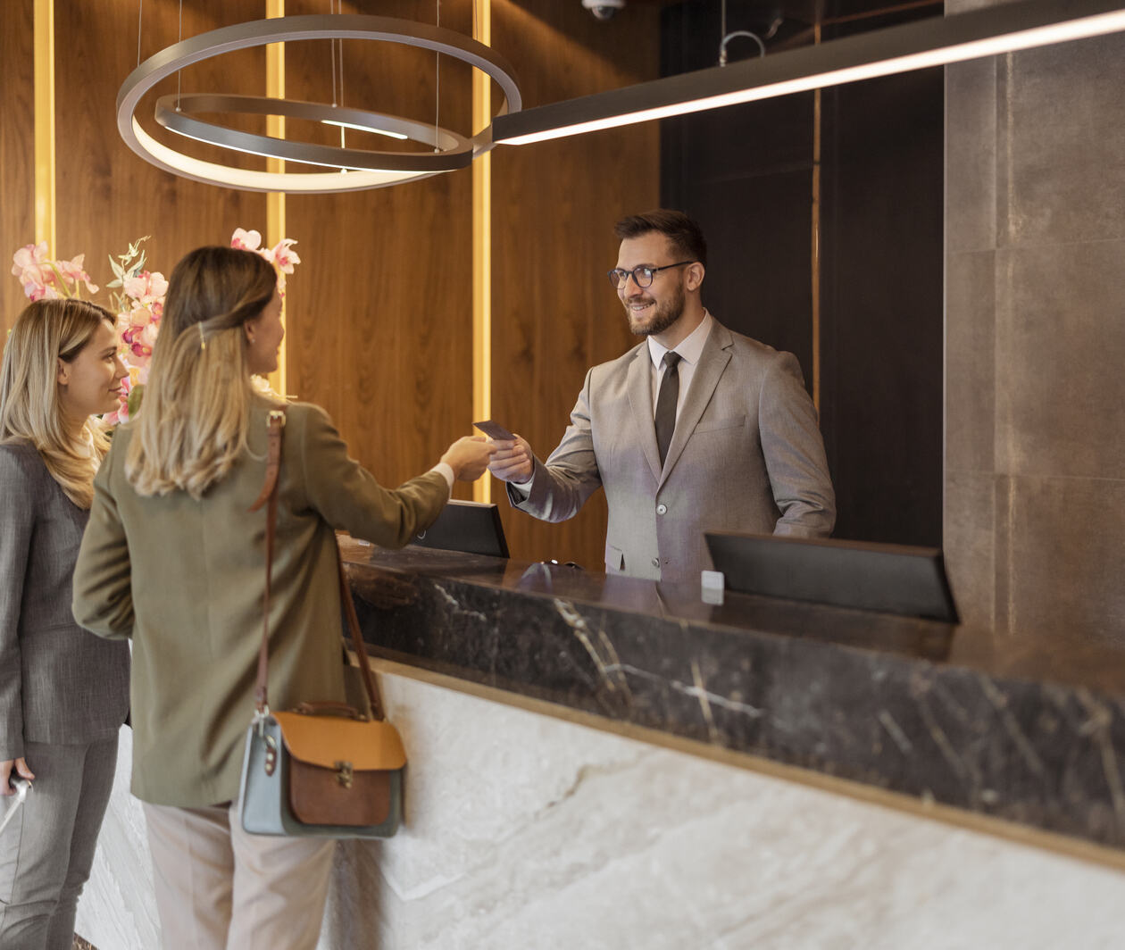 Two women at the luxury hotel desk speaking to a male member of staff