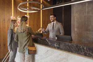 Two women at the luxury hotel desk speaking to a male member of staff