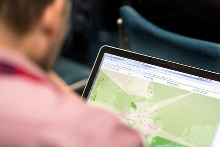 a person looking at a screen showing a map with some data insights, which are illegible 