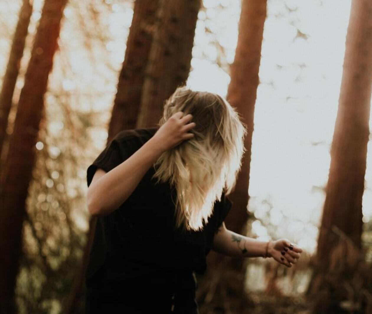 woman in black shirt standing near a forest during daytime