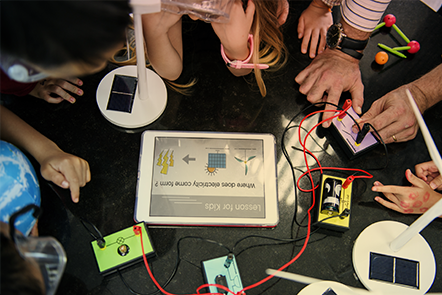 Estudiantes jóvenes que utilizan equipos de ciencias físicas y una aplicación en una tableta común 