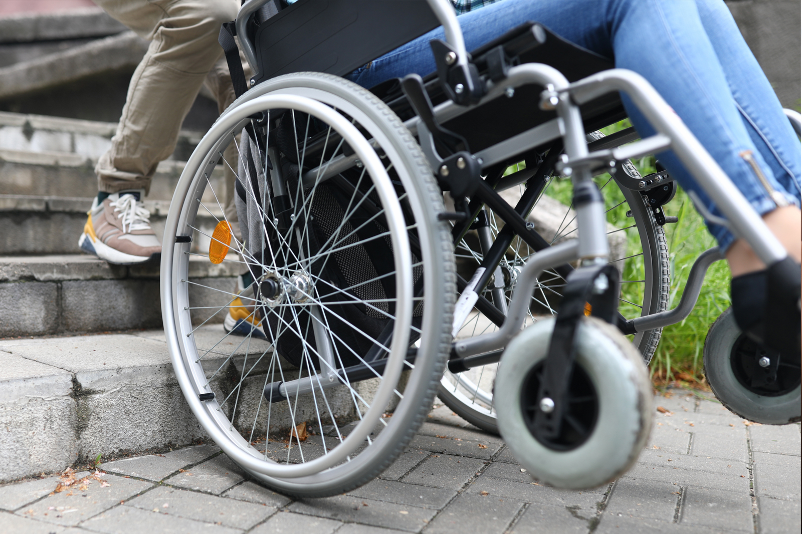 Close-up of a wheel chair being pulled backwards up steps