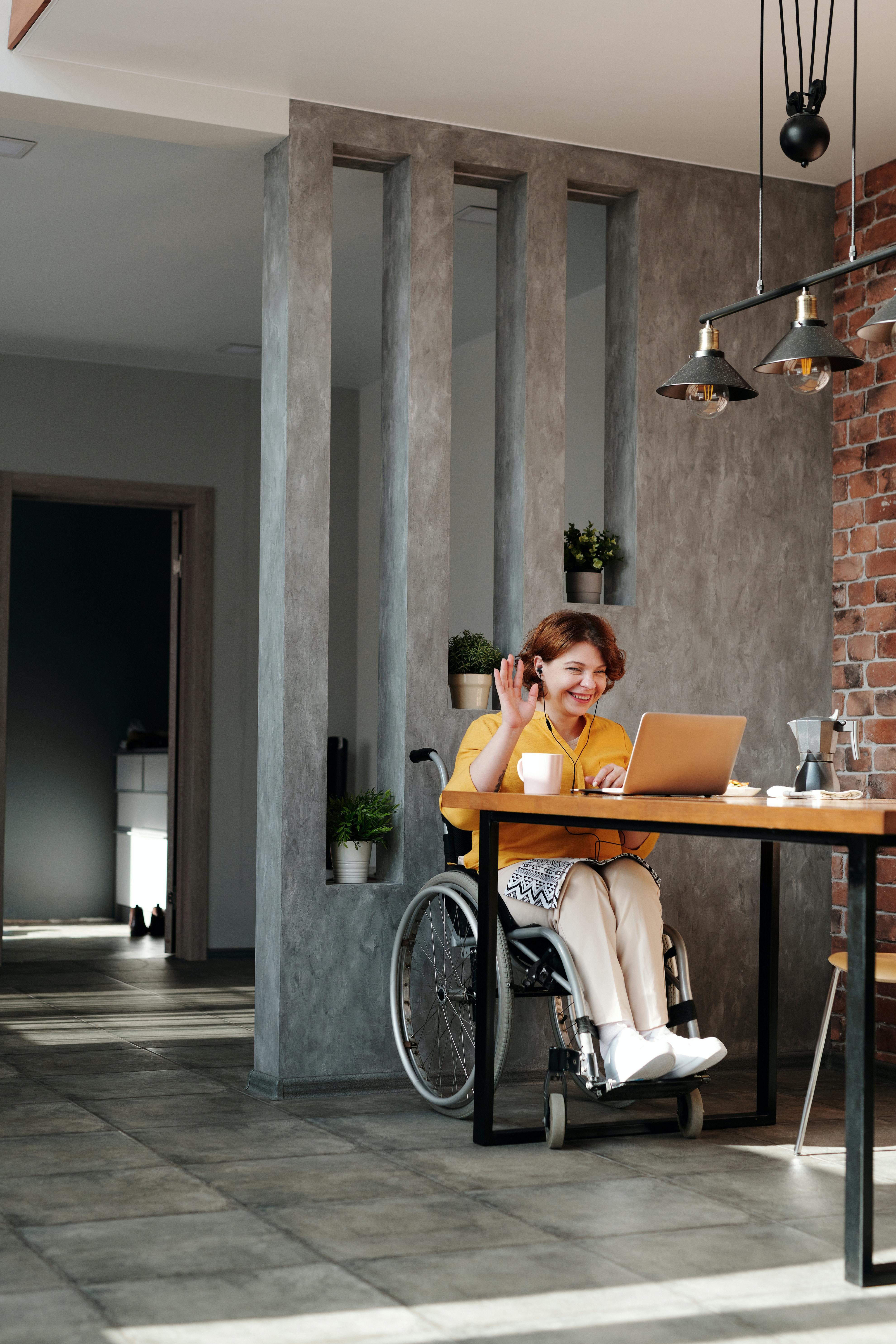 Young person using a laptop and waving hello.