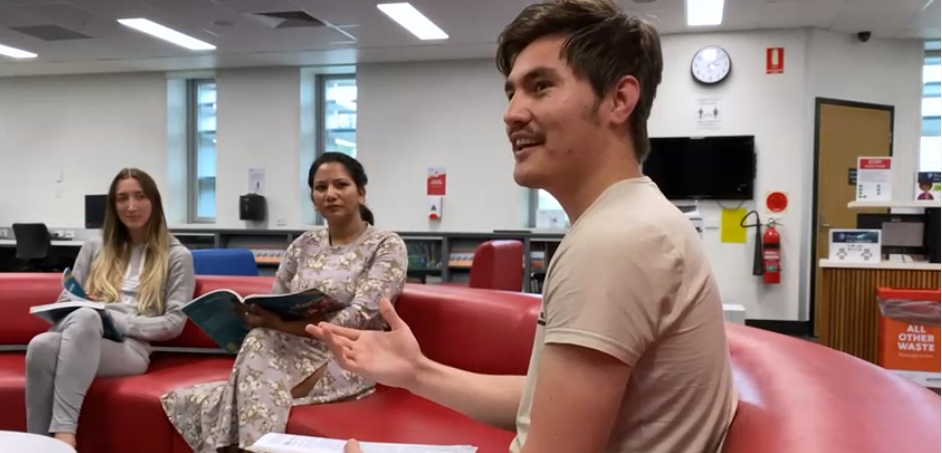 Two females and a male international student sitting on a red couchin discussion