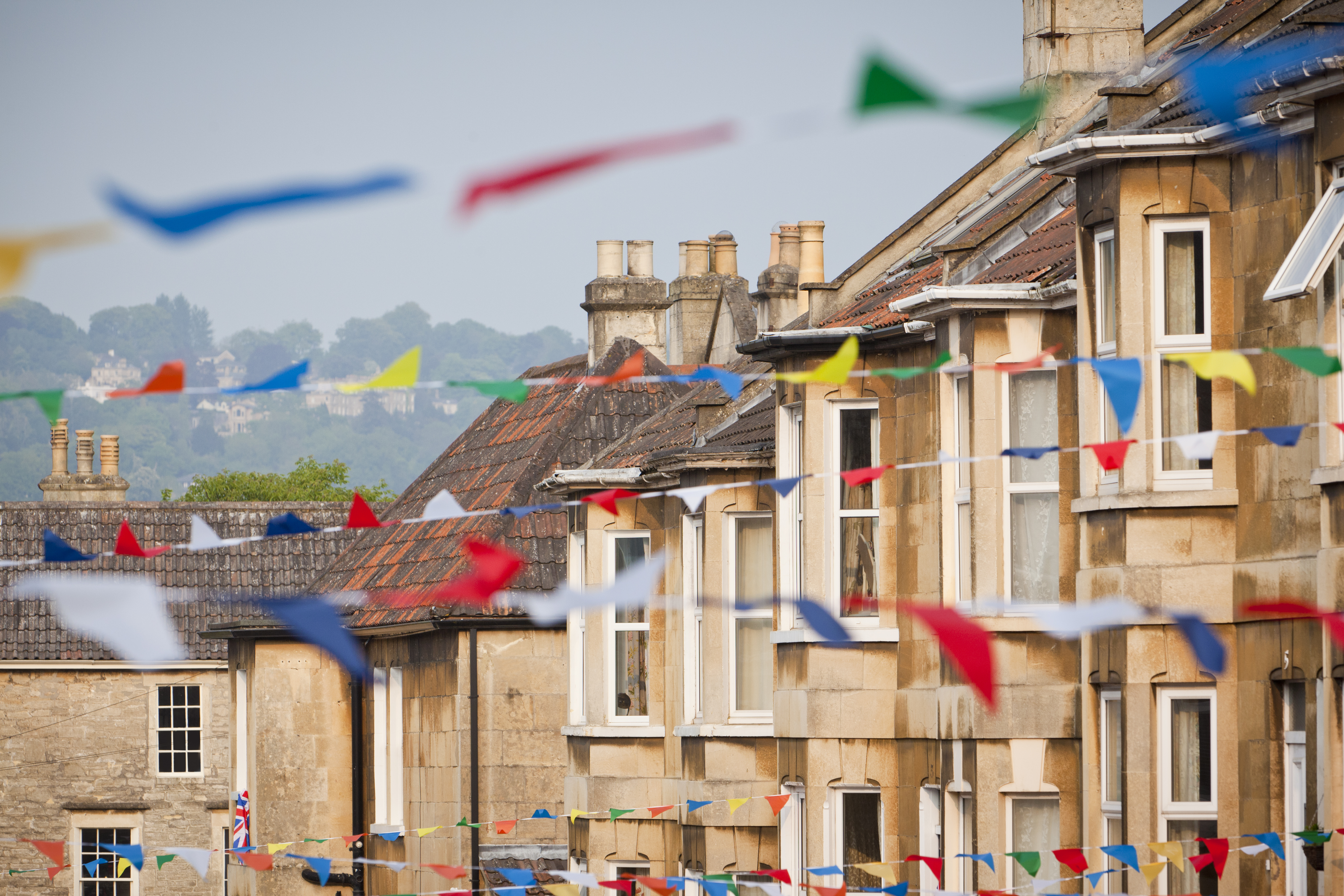 A row of houses with colourful bunting draped between each house.