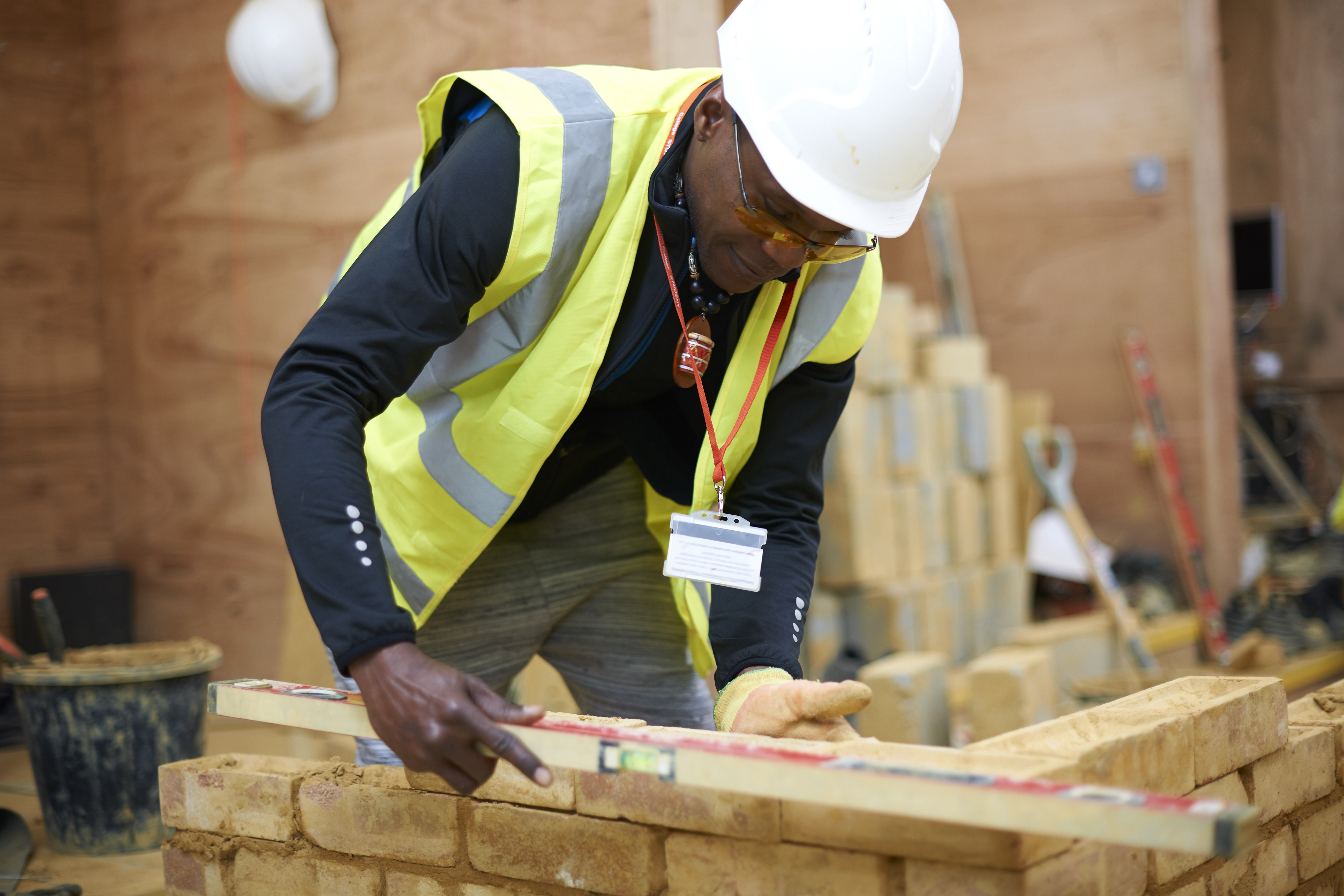 Male construction worker building brick wall with high vis and hard hat on