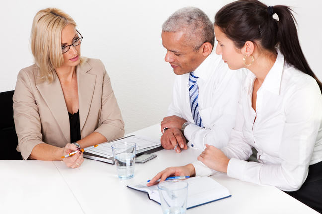 Financial planner is seated at a table, advising a married couple.