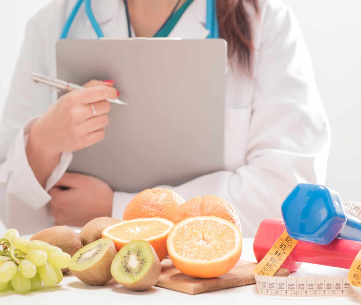 Clinician holding clipboard in front of healthy foods and exercise equpment