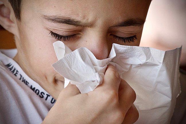 child sneezing into a tissue