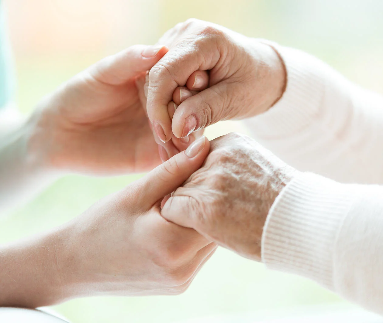 Closeup of hands of young nurse holding hands of an senior lady