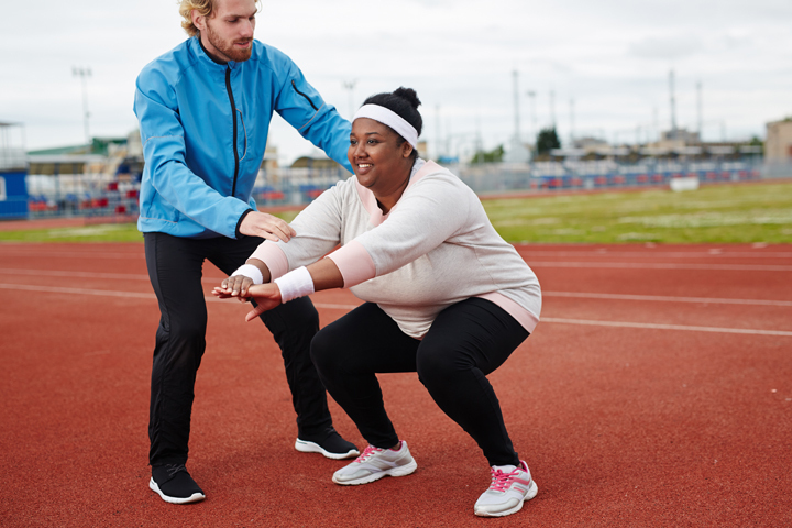 Woman from an ethnic background exercising with trainer.