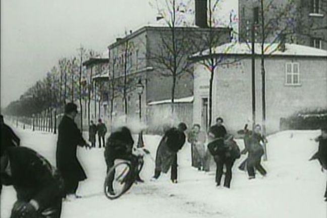 Black and white still image from Snowball Fight film scene - Louis Lumière c. 1895 - 1897. Group of people having a snowball fight in the street.