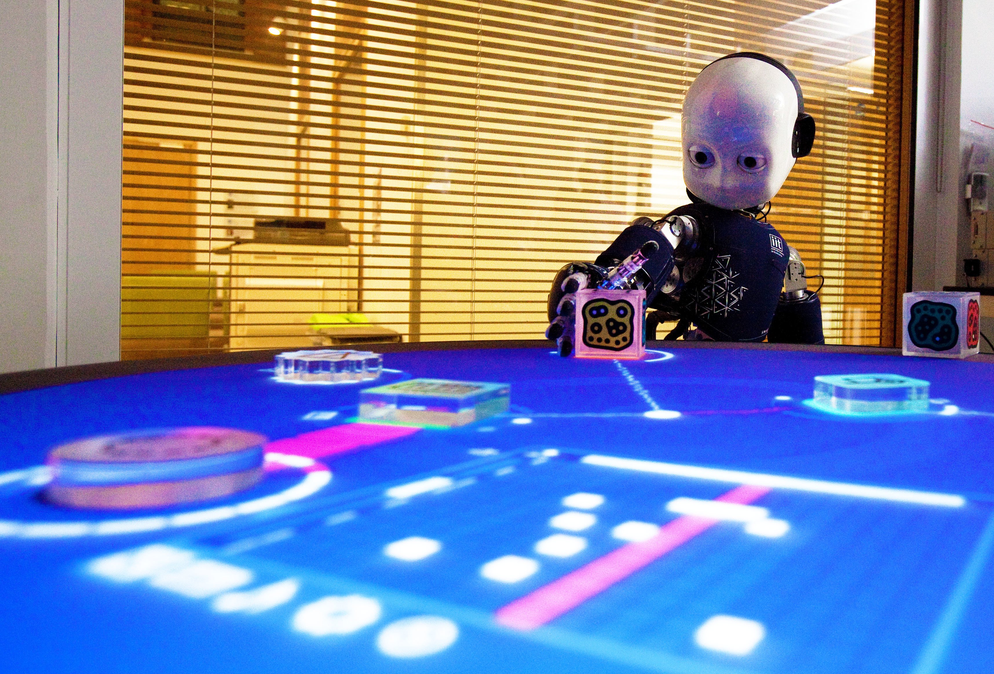 A child-like iCub robot plays a game where it learns how to match shapes to corresponding places on a light-up board